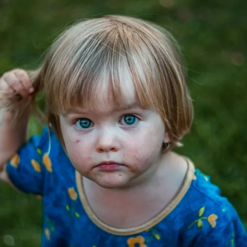 selective focus photography of girl holding her hair playing in the backyard